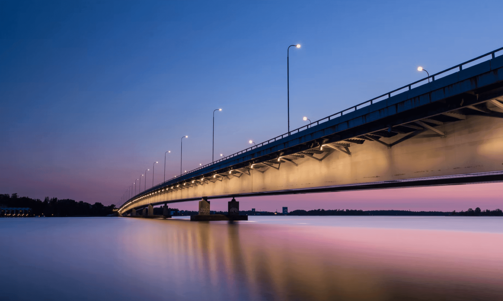 Long bridge connecting two islands over the river while the sun sets.