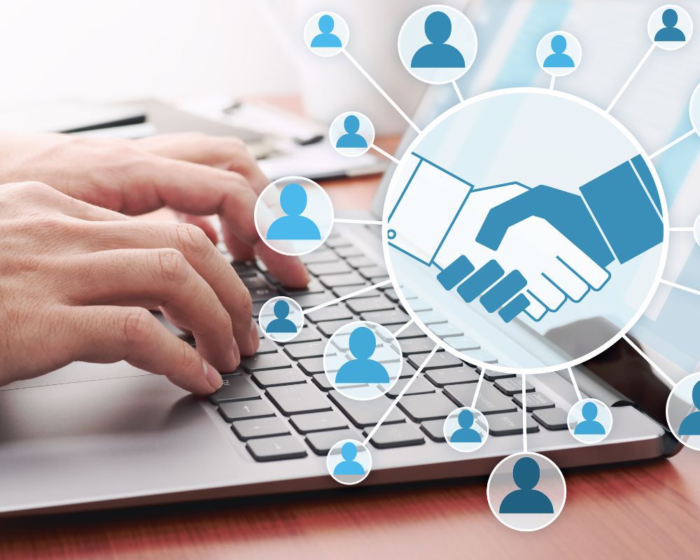 Hands typing on a laptop with overlay icons of networking and a handshake, symbolising professional connections and online communication.