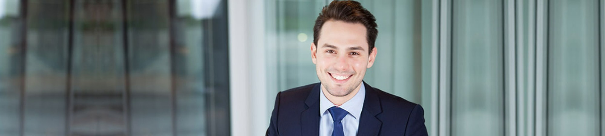 Main banner image of a man in a suit smiling in an office setting.
