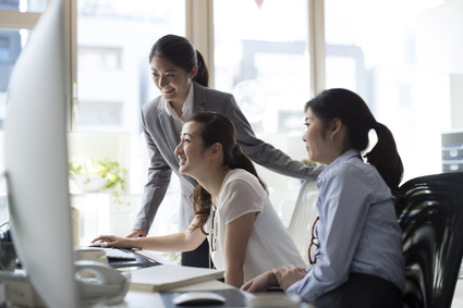 Group of asian businesswomen in front of a monitor and laughing.