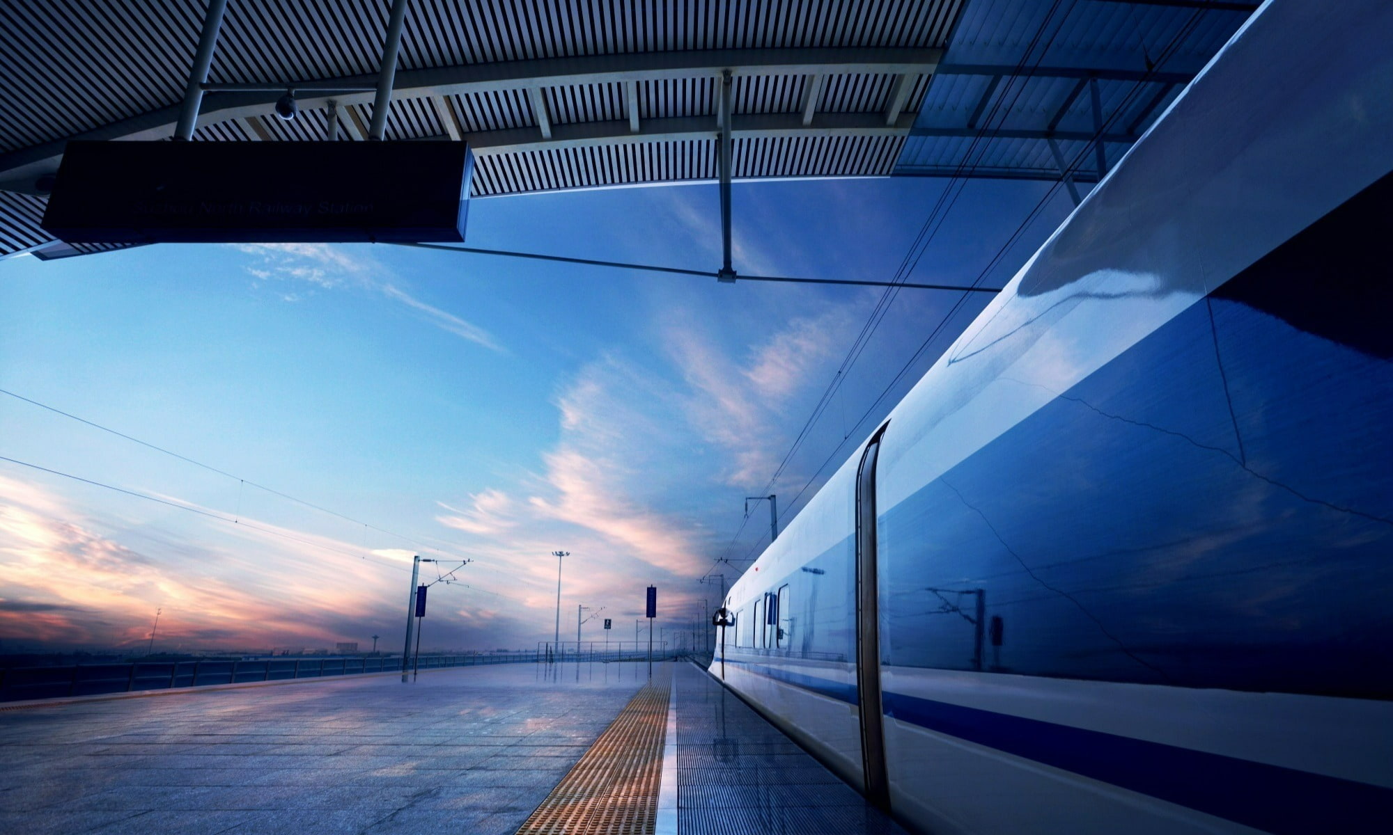 Stationary train at the train station while the sun sets.