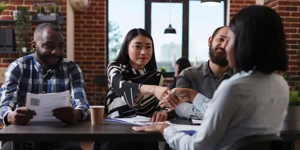 People around a table shaking hands