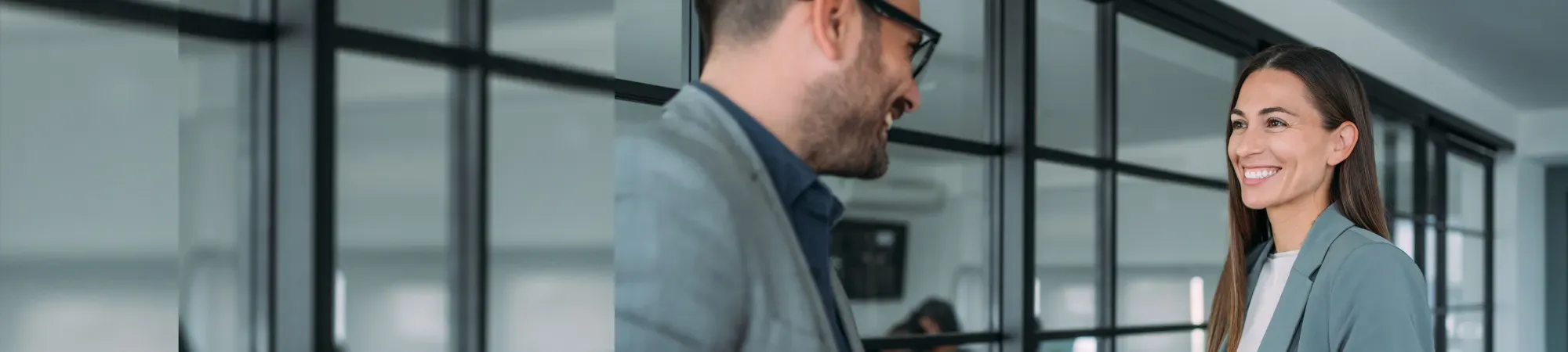 Two colleagues smiling at eachother wearing grey