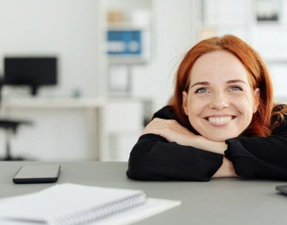 relaxed red hair woman with head in hands smiling 