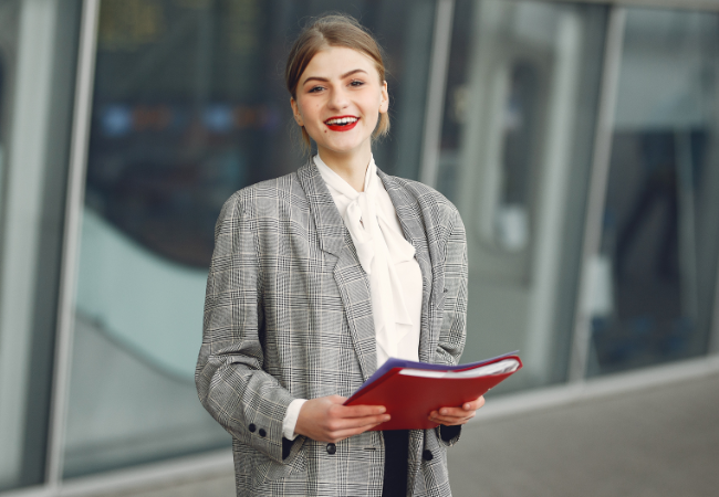 Smiling woman holding a red file.  