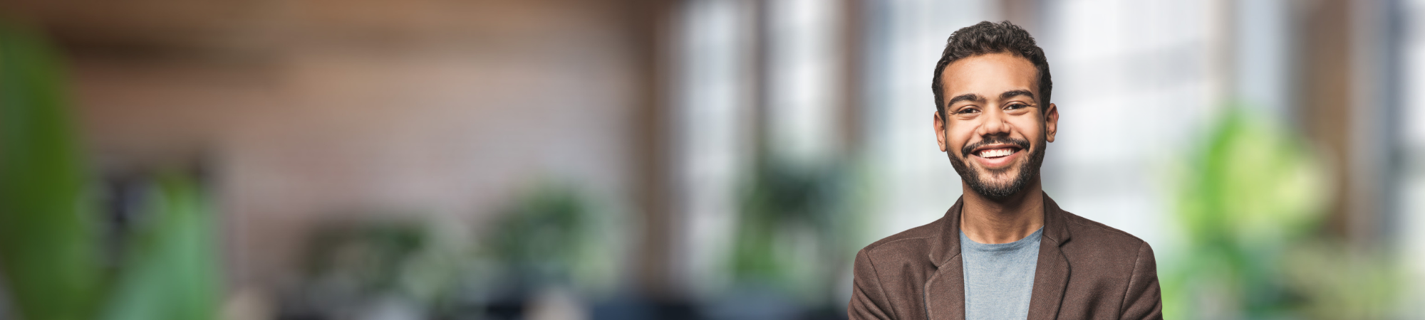 Smiling male professional wearing brown jacket.