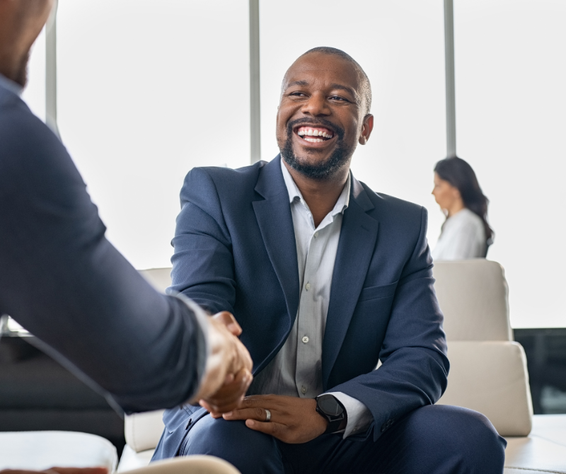 Smiling professional shaking hands during a meeting, representing the importance of networking for career growth.