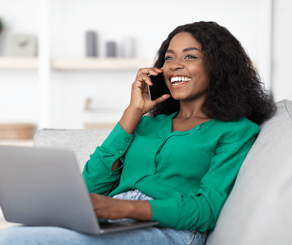 women on a sofa with a laptop talking on phone