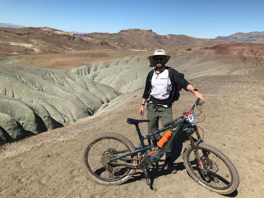 Richard Duke during the Andes-Pacifico MTB race in Chile, standing with his mountain bike in a rugged desert landscape.