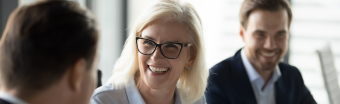 Woman smiling while talking to another woman and man.