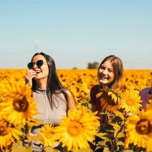 happy smiling girls in sunflower field 