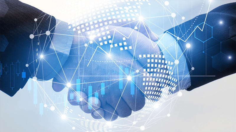 Two business professionals shaking hands overlaid with futuristic digital graphics, symbolizing a merger between human collaboration and advanced technology in the business world.