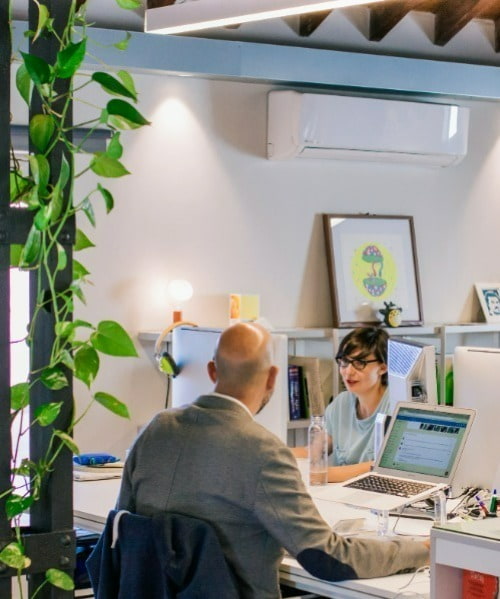 Two colleagues speaking to each other at vibrant office while working