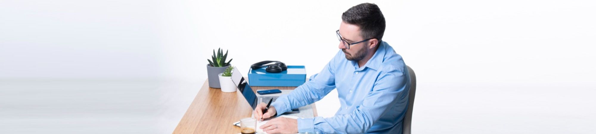 Man at desk with laptop writing