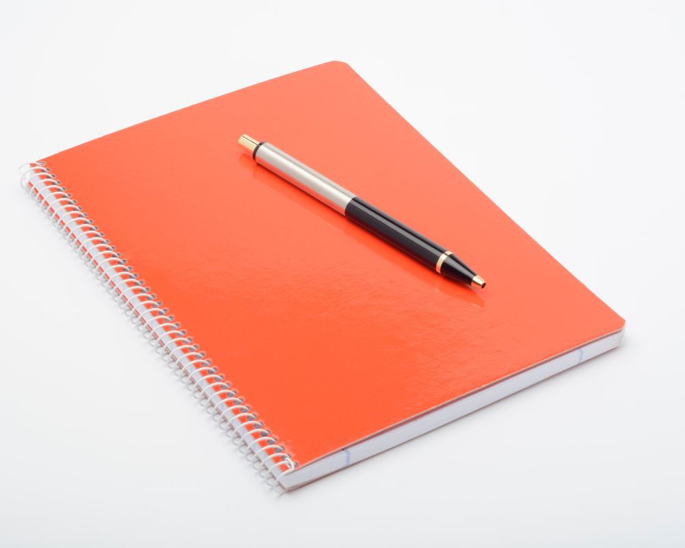 An orange notepad plus pen