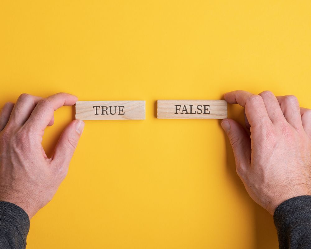 A pair of hands holding wooden blocks labeled “TRUE” and “FALSE” against a yellow background, symbolizing the process of debunking misconceptions about retained search.
