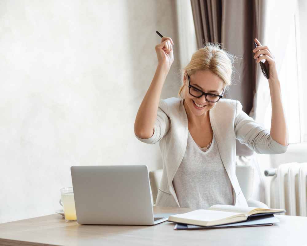 Woman sitting at the desk celebrating a small win