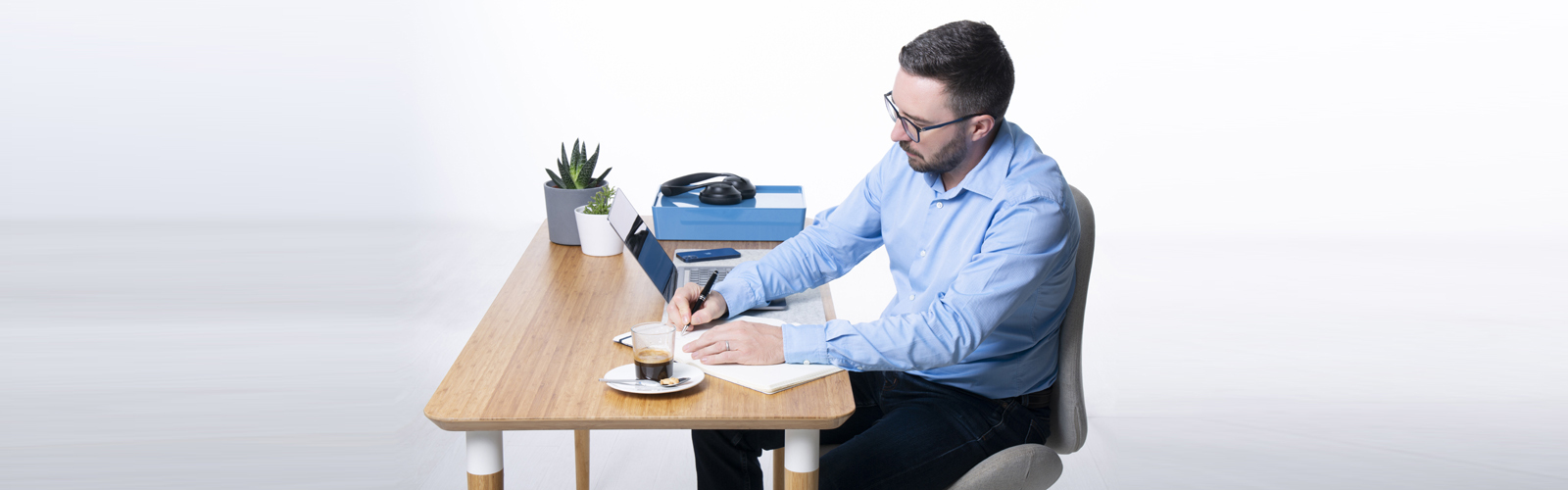 Expert recruiter working at a desk, writing and using a laptop to manage business tasks