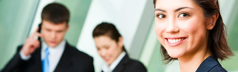 Smiling employee at work in front of two colleagues in background