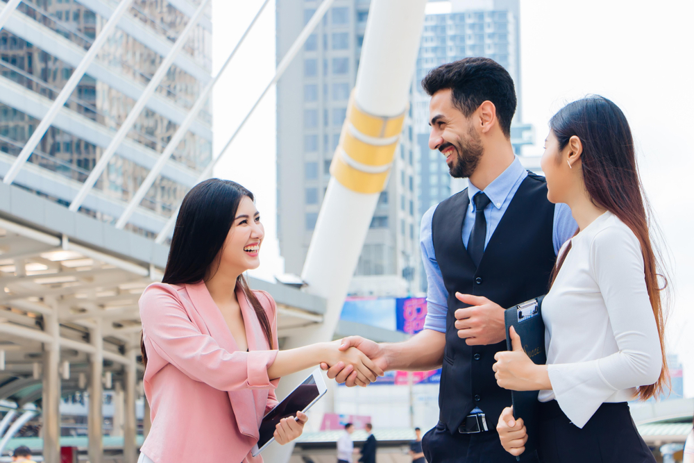 The head of a foreign man is shaking hands with an Asian female subordinate.