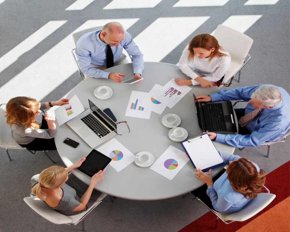 Team shown at a round desk from above