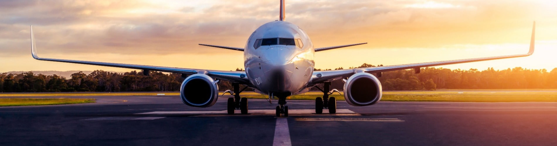 Airplane taking off at runway while the sun sets.