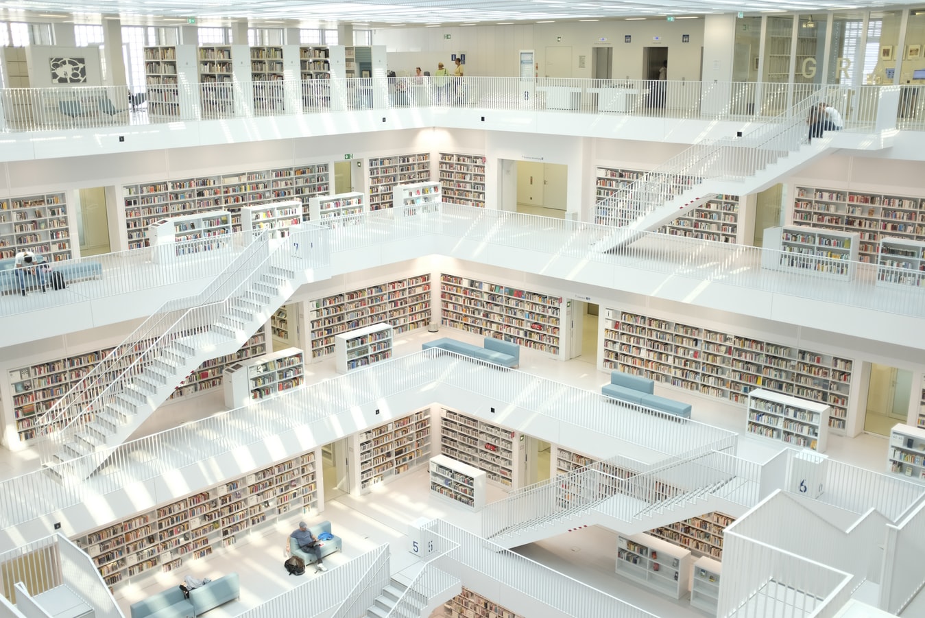 Seeking books in white library with four stories