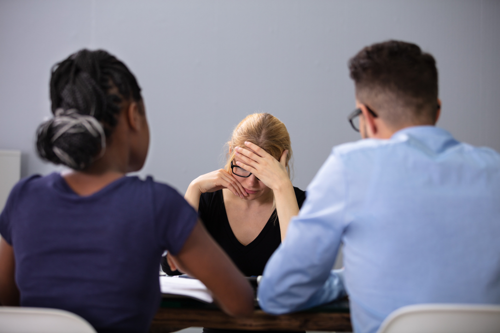 Young unhappy woman sitting in front of managers