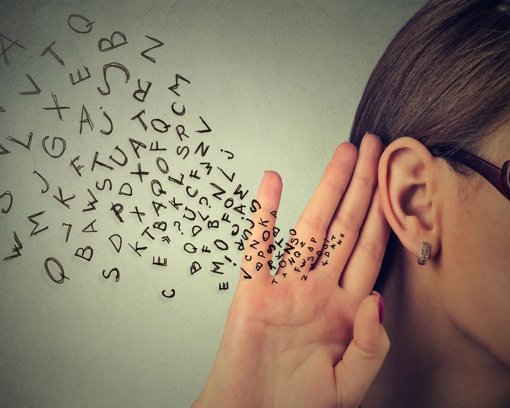 Lady listening to sounds in the form of letters to her ear