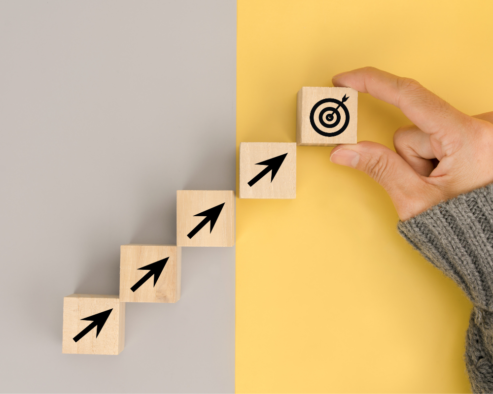 Wooden blocks with arrows pointing upwards on a gray and yellow background.