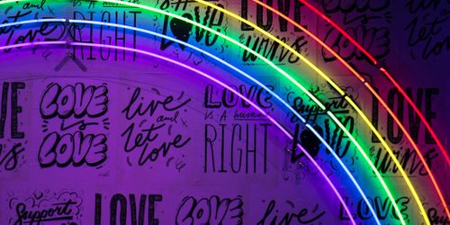 Rainbow in front of wall with "love wins" written on it