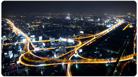 aerial view of a city at night with lit up roads like arteries