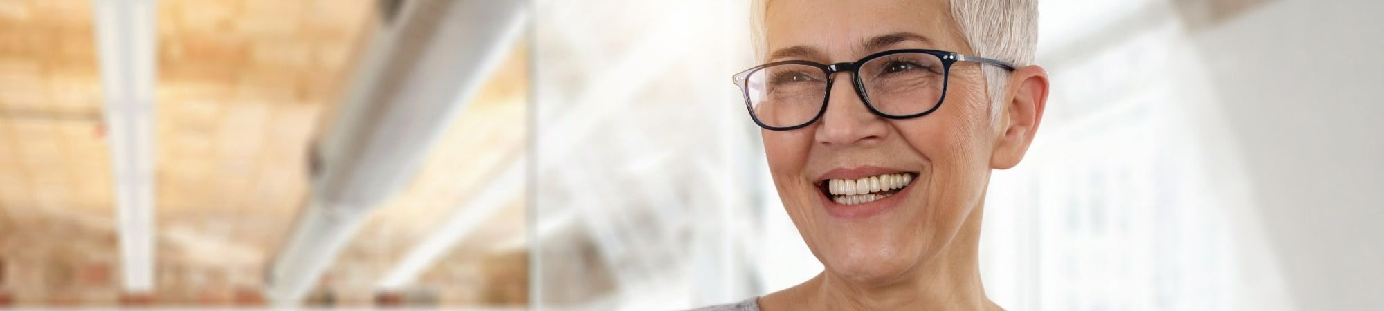 mature age professional woman in modern glasses smiling in an office