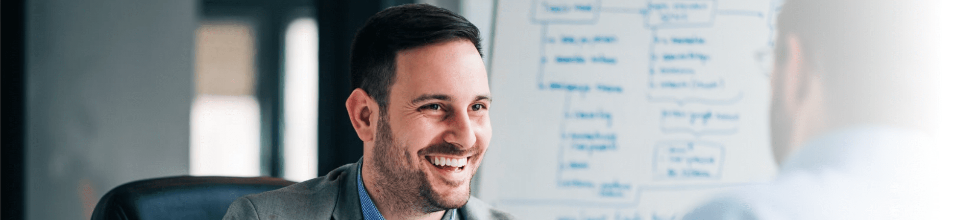 Employee smiling at another person during a finance meeting.