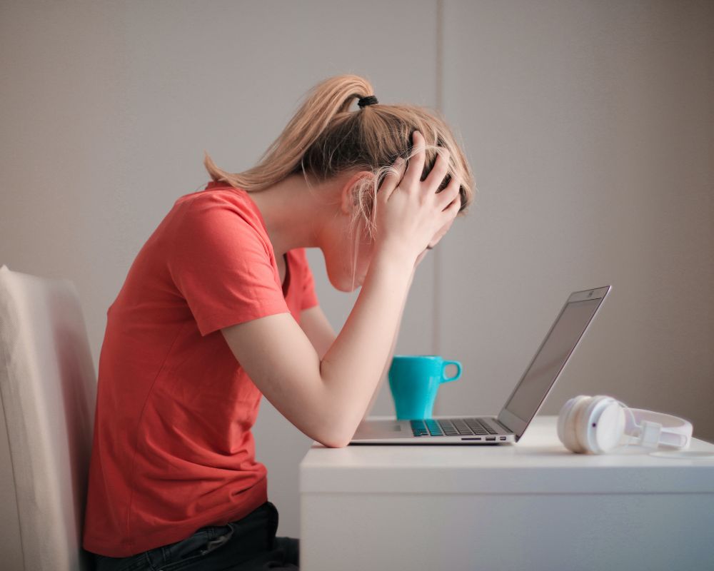 Woman sitting at the desk holding her head in stress.