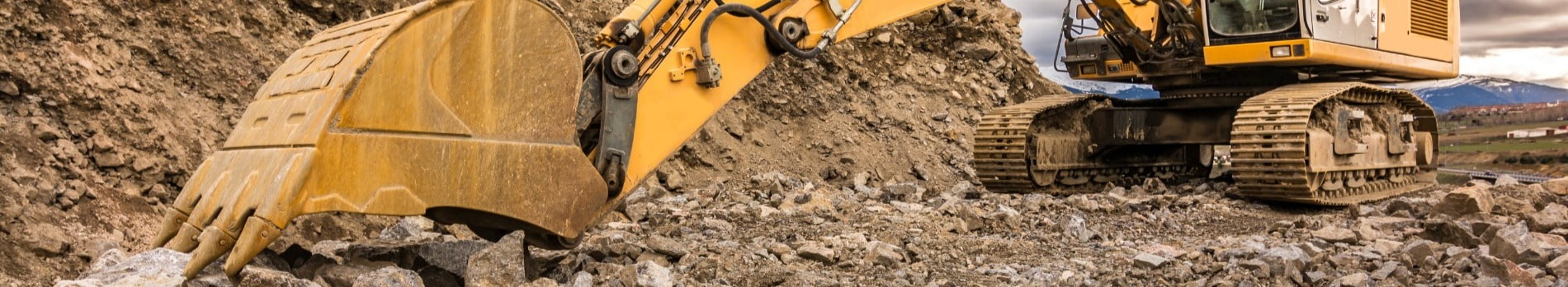 Large yellow mining excavator digging through mine site