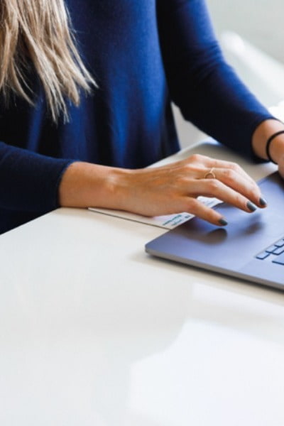 Person in a blue jacket typing on laptop. 