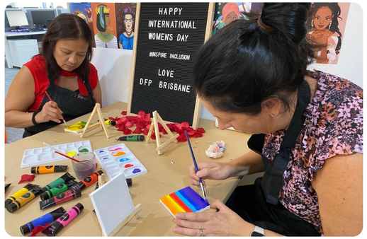 two woman painting on small canvases