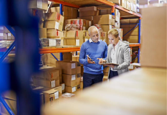 Two employees lookng at a clip board in a factory.