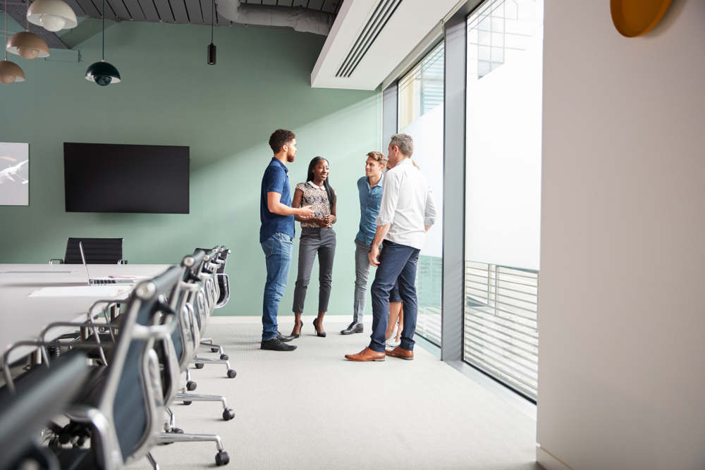 casually dressed businessmen and businesswomen having informal meeting in modern boardroom