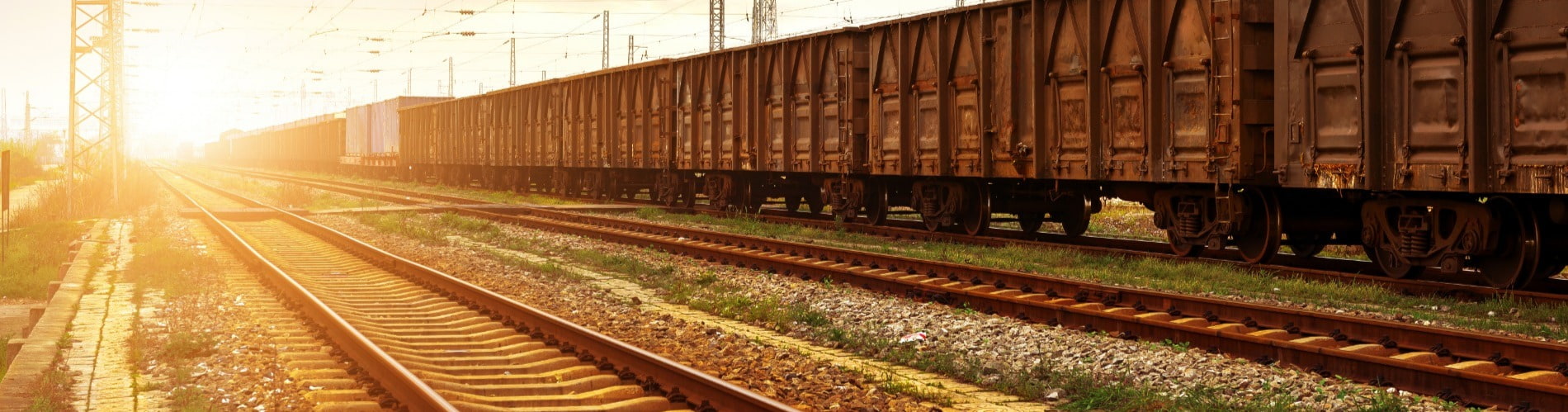 Railway tracks with freight trains passing by and sun shining